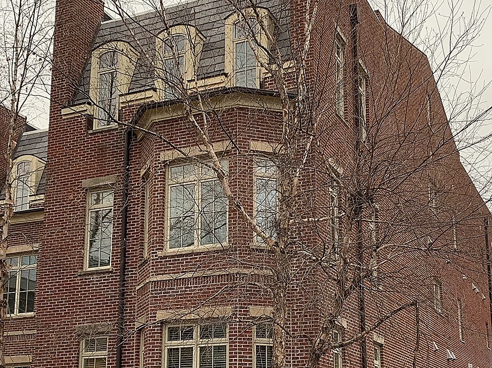 The corner bay of The Row in 2021, red brick carrying from a rusticated stone base past two levels of windows to dormers set in a slate roof.