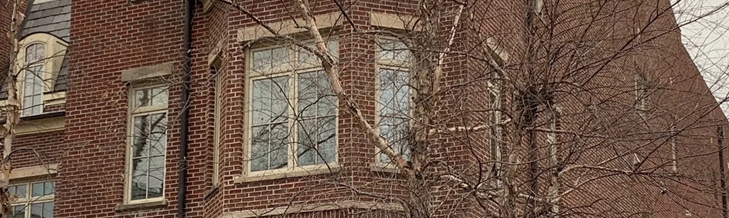 The corner bay of The Row in 2021, red brick reading as one range from the stone base up past the window bay