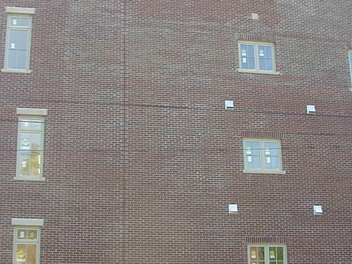 The end wall in 2004, its red brick clouded with purple and pale patches across the courses above a parked pickup