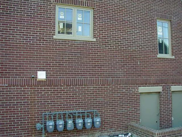 A side wall in 2004 after the blend, red brick even above and below a soldier course, with a bank of gas meters at grade
