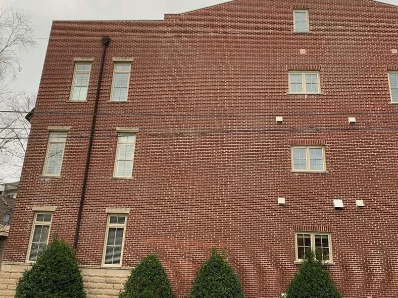 The same stepped parapet wall in 2021, the brick one red range from the stone base to the roofline with clipped shrubs planted below