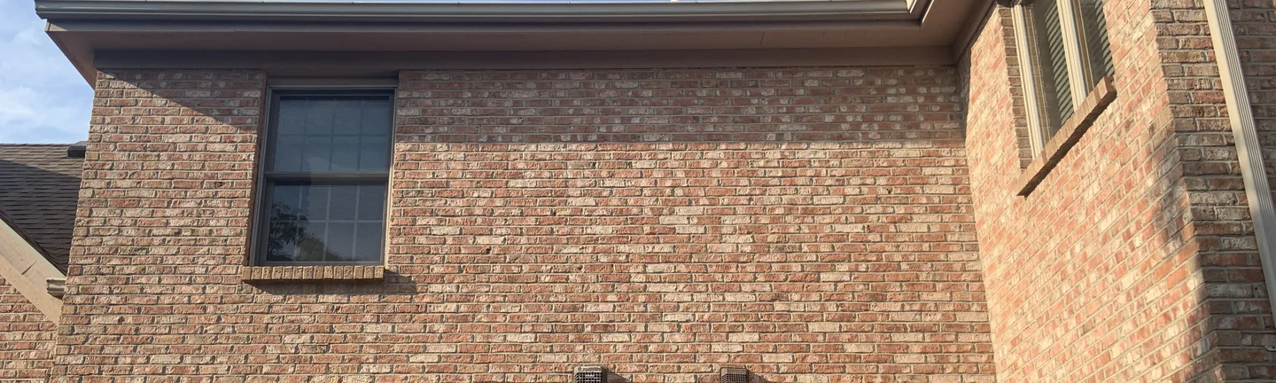 The back wall of the house in 2019, the brick running as one range of tan, cream and red under the eaves