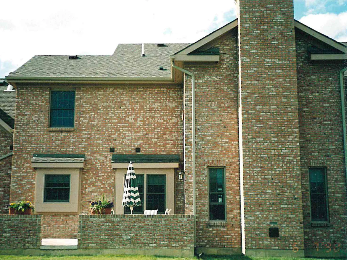 The back of the house in 1998, the brick reading as a flat buff tan with pale units scattered across the wall, the chimney and the patio wall below