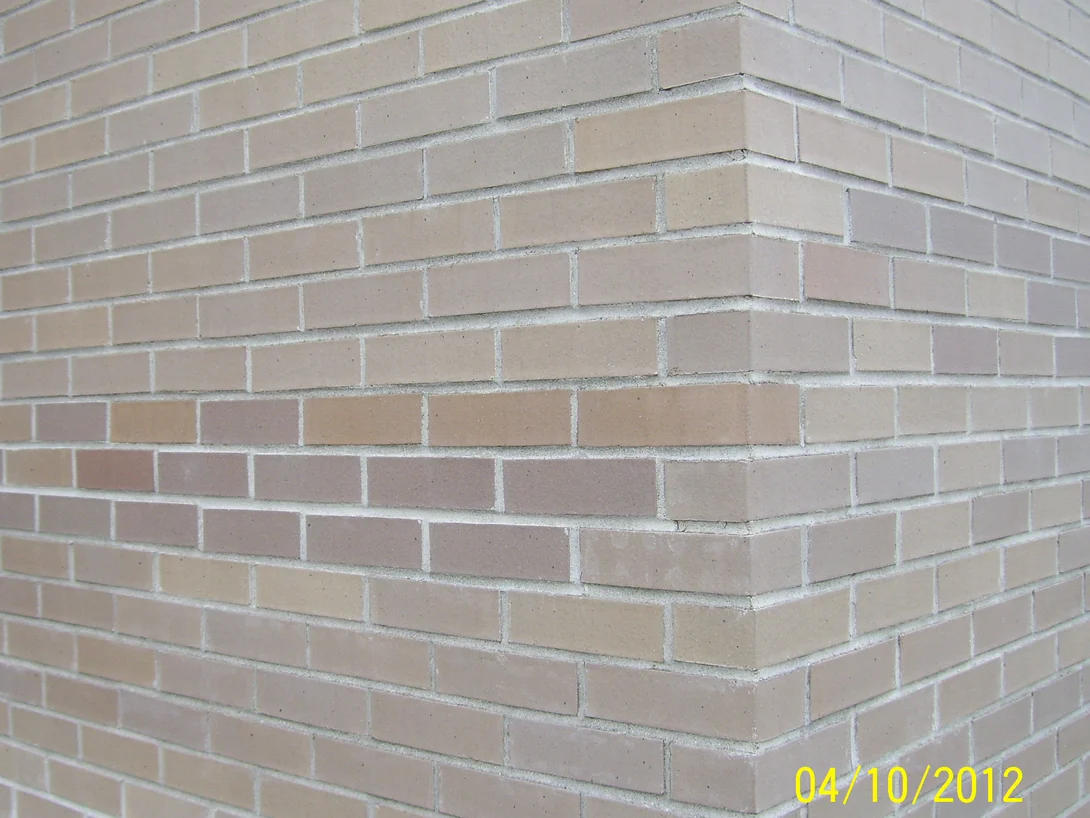 An outside corner of the same brick at close range in 2012, individual units in mixed creams, tans and pinks with pale mortar joints