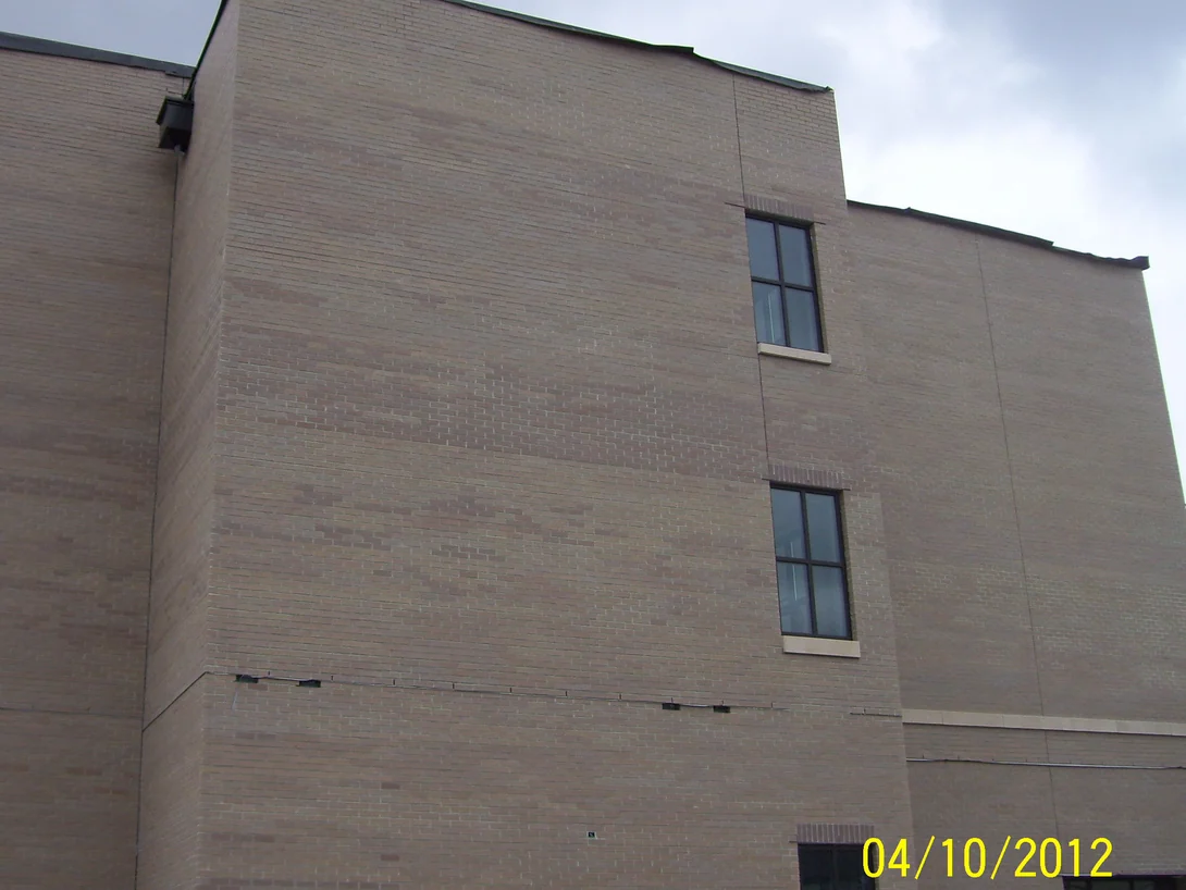 The blank end wall of the building in 2012, its buff brick carrying broad darker and lighter patches across three storeys