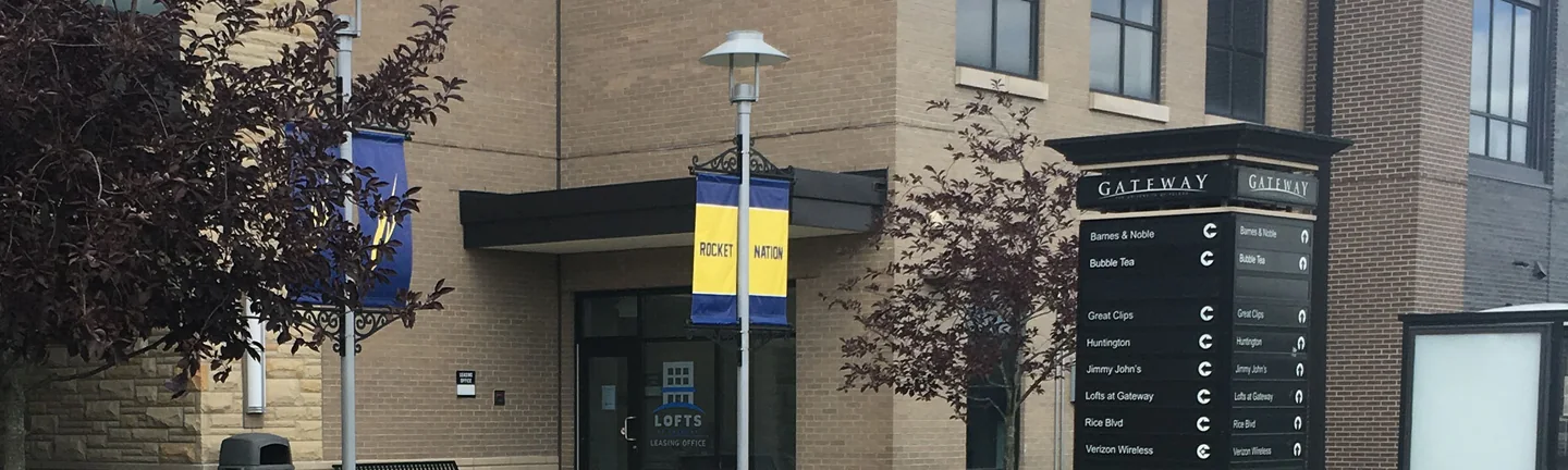 The Gateway entrance in 2019, banners and a tenant directory standing in front of buff brick that reads as one even range