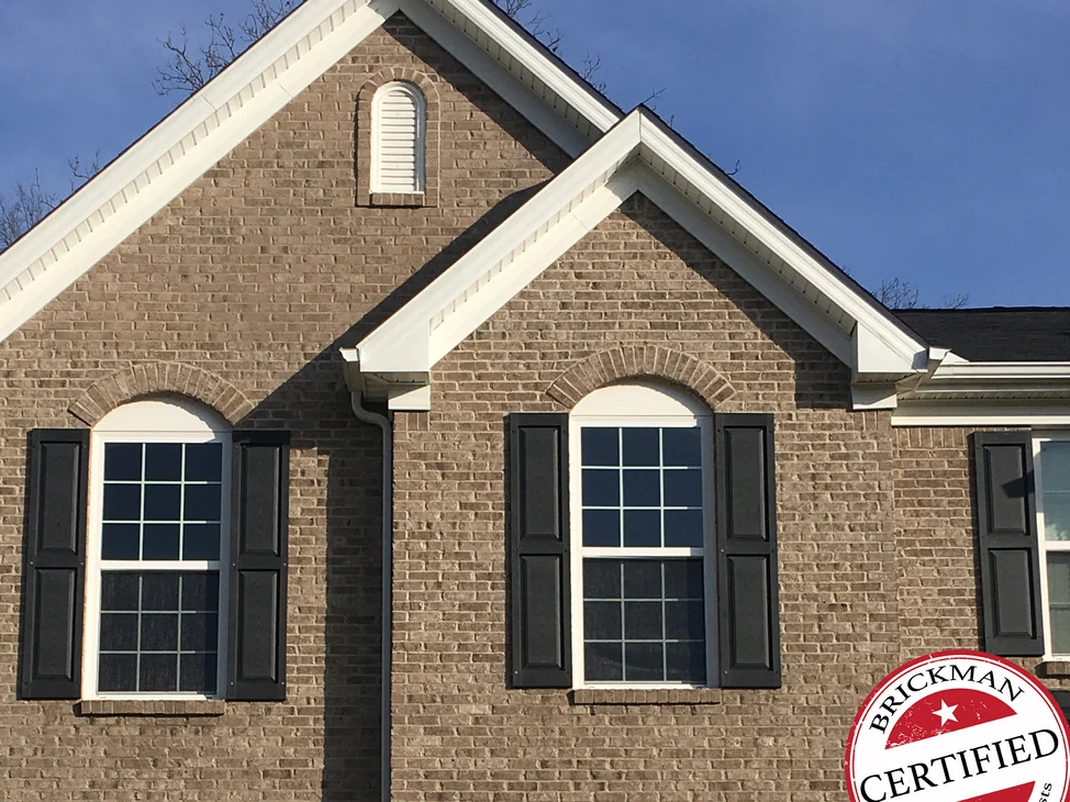 The two front gables of the Uniontown home in 2020, peak and wall reading as one run of brick, the certification stamp in the lower corner