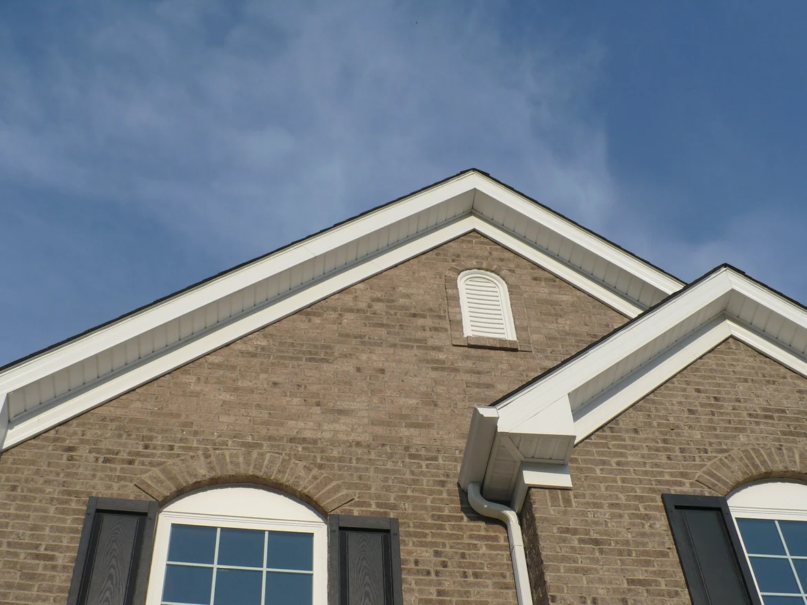The two front gables of the home in 2012 before staining, the brick in the upper peak around the louvered vent reading lighter and pinker than the wall below the windows