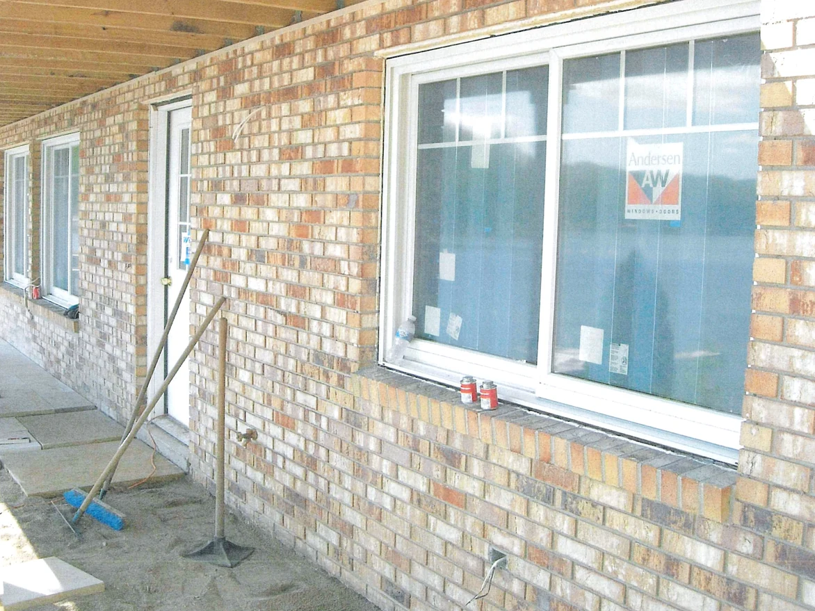 Close view of the same wall under the porch ceiling, the units running pale cream, buff and tan with grey mortar joints