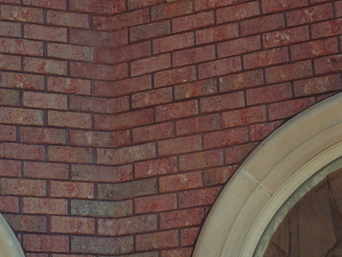 The inside corner of the wall in 1999, the shaped corner units reading grey and brown against the red field brick, with a cast stone arch at the lower right