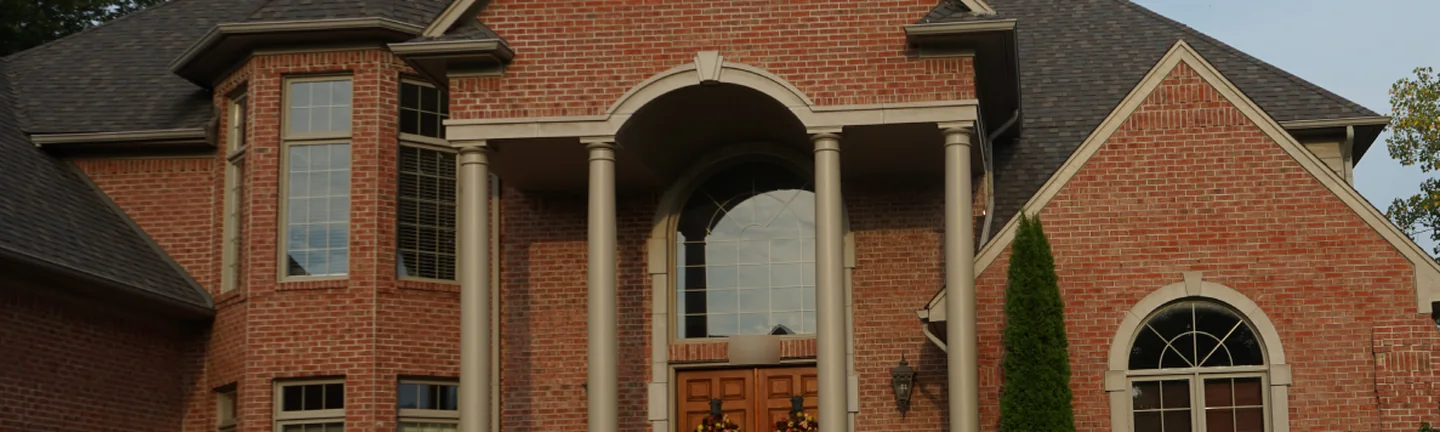 The front of the house in 2019, red brick running across the entrance gable, the columned portico and the bay window as one range