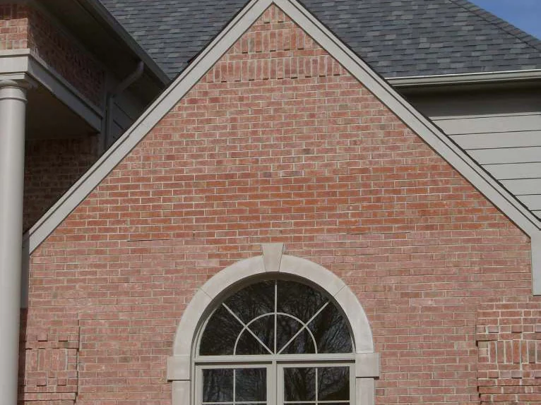 A side gable over an arched window in 2007, a darker patch of brick near the peak and a lighter patch below it in the pale pink wall