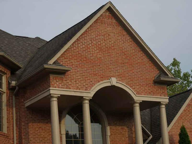 The entrance gable above the portico columns in 2019, the brick one even red range under an overcast sky