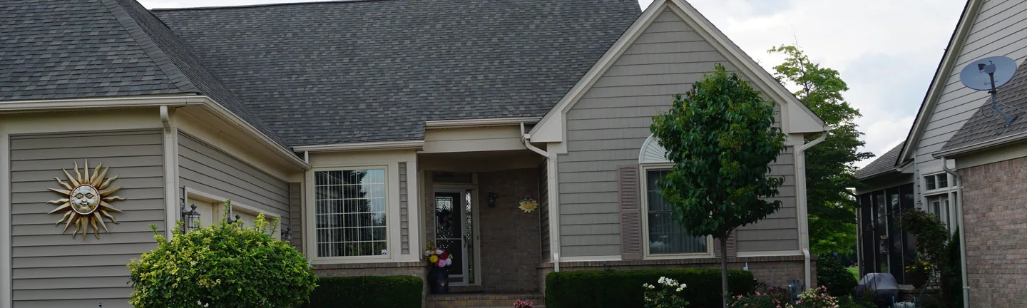 The front of a single-story home in 2019, brick and siding under a low grey roof, the brick one even light tan range