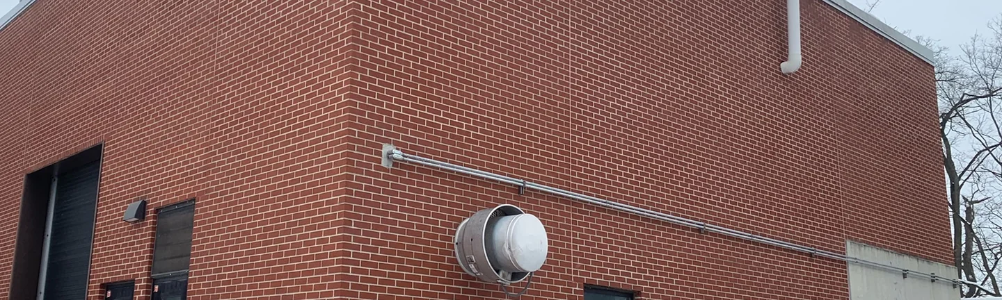 The corner of the waste water plant building in 2021, red brick reading as one range across both elevations under a metal coping
