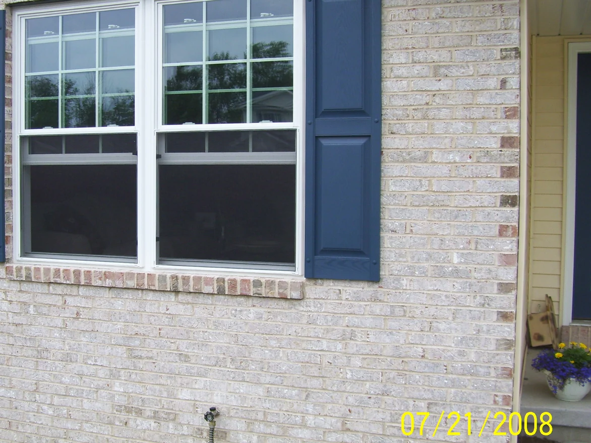 The double window on the Waterford house on 21 July 2008, light brick with a course of dark red-brown headers under the sill and scattered dark units in the wall, navy shutters either side