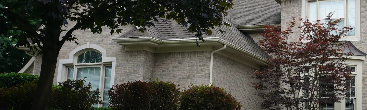The front wall of the West Bloomfield house in 2019, the brick running as one buff and gray range past an arched window and a bay