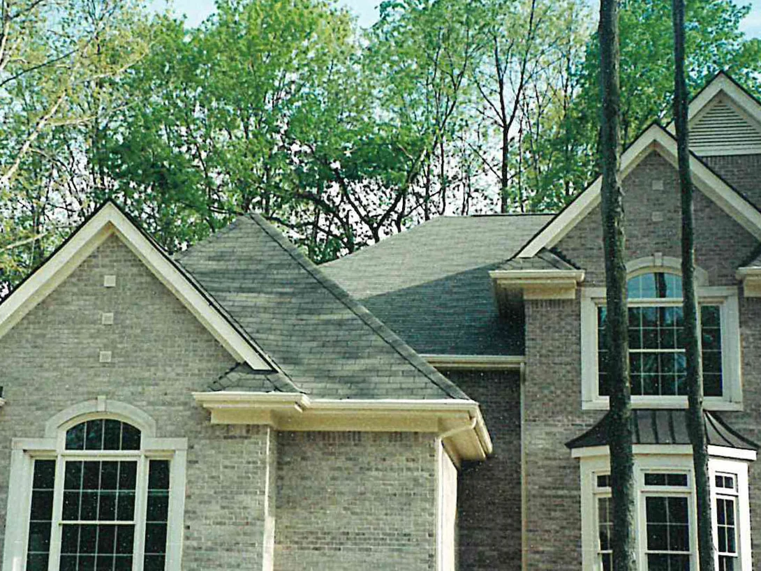 The house from the street in 1999 while the work was under way, its brick reading gray and uneven across the near gable and the wing behind it