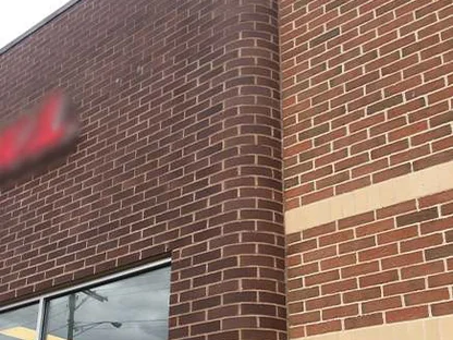 The rounded corner in 2021, its units reading the same red brown as the field brick and buff band on the return wall beside it