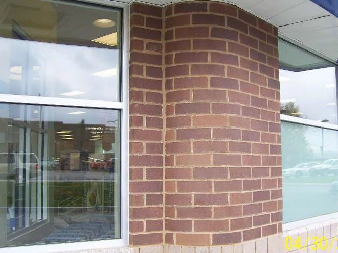 Close on the rounded brick corner in 2008, its units blotched paler and pinker in places against the darker brick around them, with a camera date burned into the bottom corner