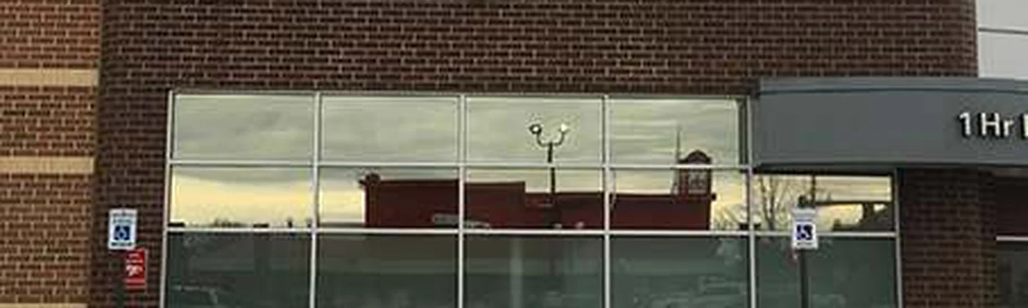 The storefront in 2021, dark red brown brick running above a long band of shop window to a rounded brick corner