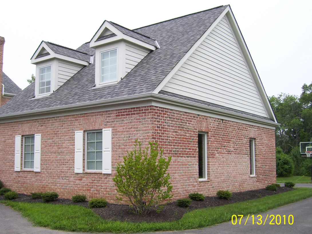 The brick wing of the house in 2010, two dormers set into the roof and a sided gable end at the right, its brick a mottled pink and red