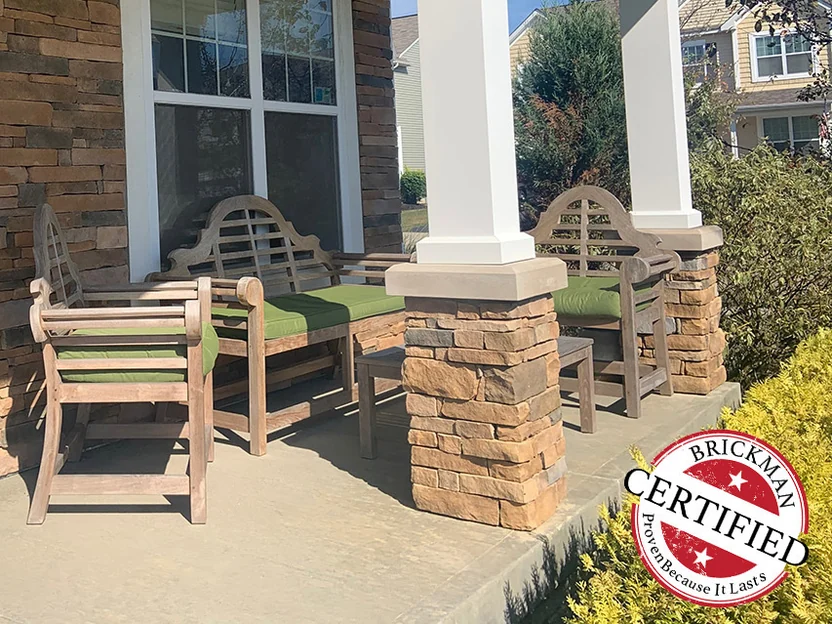 The covered porch in 2019, the stone column bases and the wall beside the window reading as one even tan and rust range