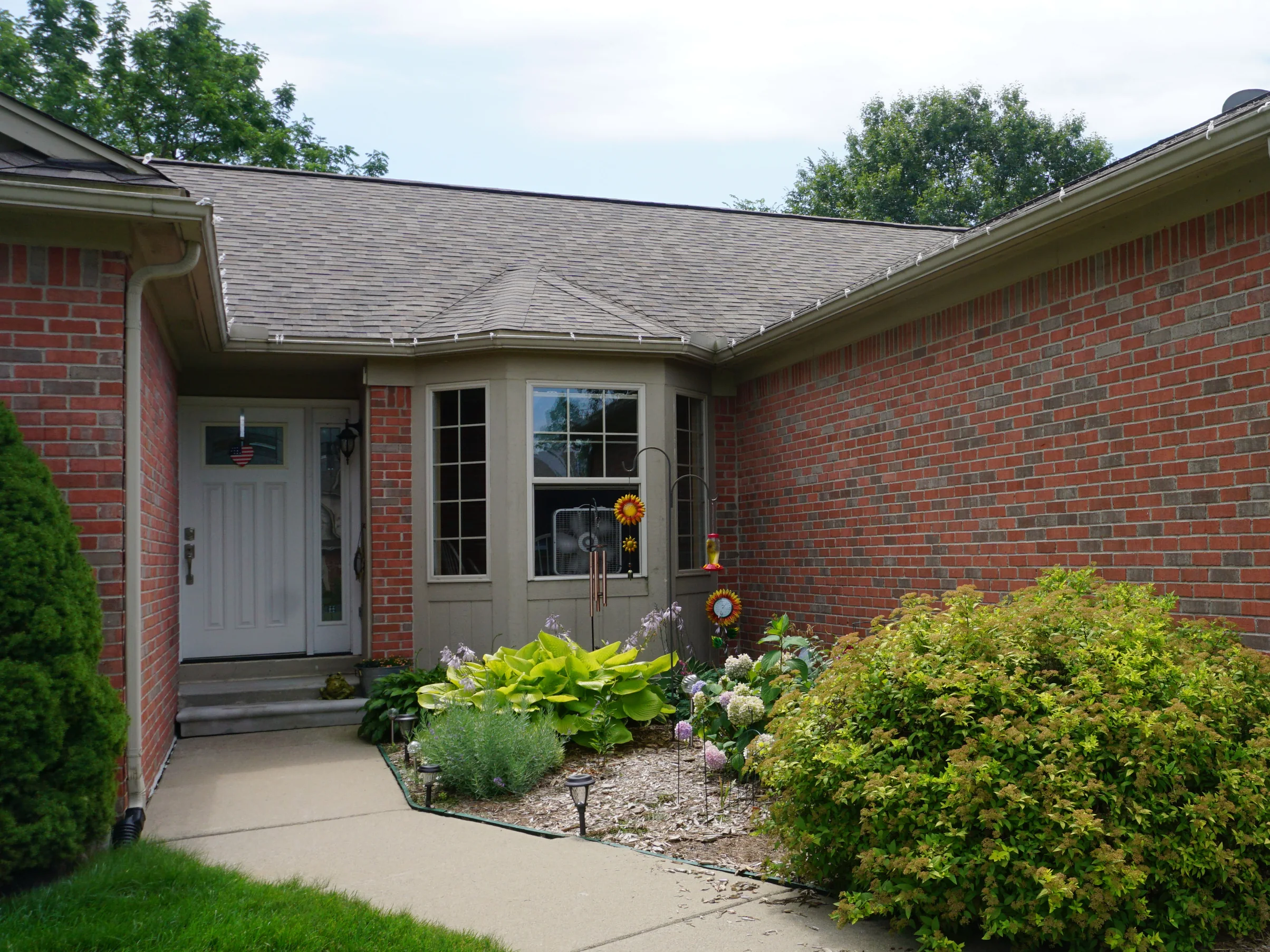 The front entry of the house in 2019, the brick at the door and along the return wall reading as one range of reds, greys and tans, with planting either side of the walk