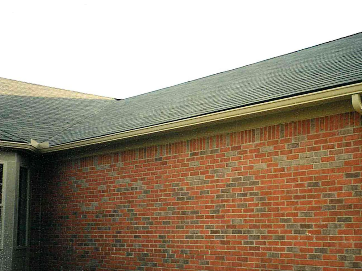 A brick wall of the house in 2001 below a roof valley, red brick carrying blended courses of grey and tan units across the elevation
