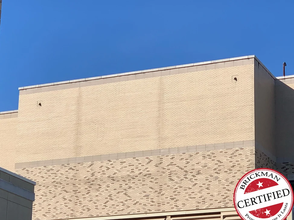 The upper wall of the hospital in 2021, buff brick one range from the coping down to the band of darker blend brick, with the certification stamp in the corner