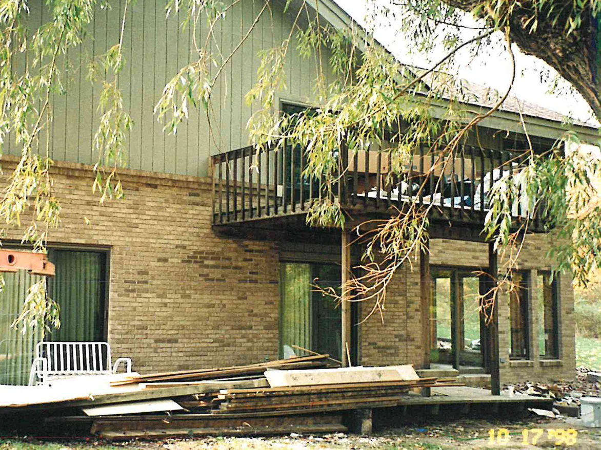 The walkout level of the same house during the work in 1998, its buff brick close to the camera with decking stacked on the ground in front of it