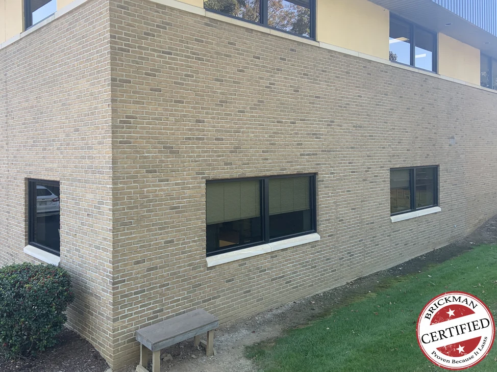 The outside corner of the office building in 2019, the brick carrying round the corner as one buff and tan range under a glazed upper storey.
