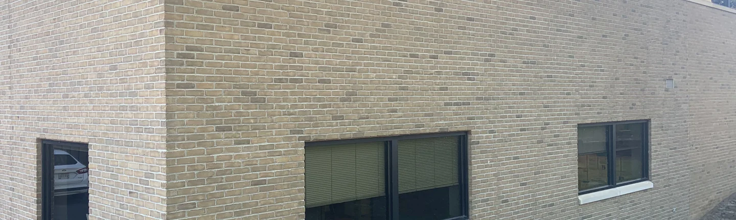 The brick of the Wooster office building in 2019, running unbroken across the wall and round an outside corner
