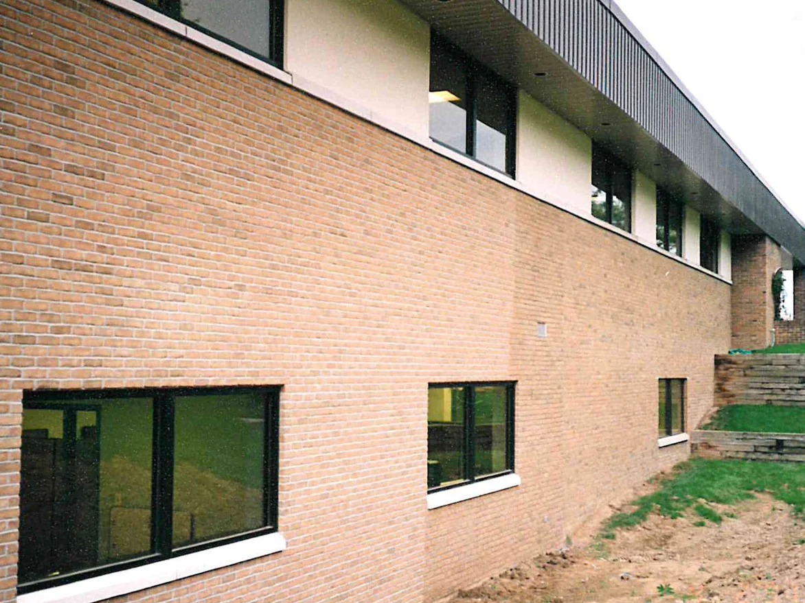 The new elevation in 1997 before the work, the brick reading as a flat pale buff running away to the wing beyond, bare soil still at the foot of the wall