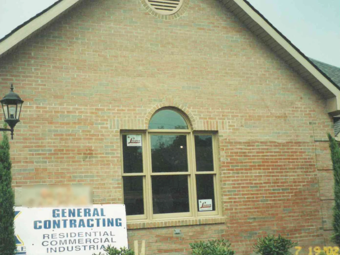 The gable end of the house in 2002, pale washed out patches spreading across the brick around an arched window and a round louver vent