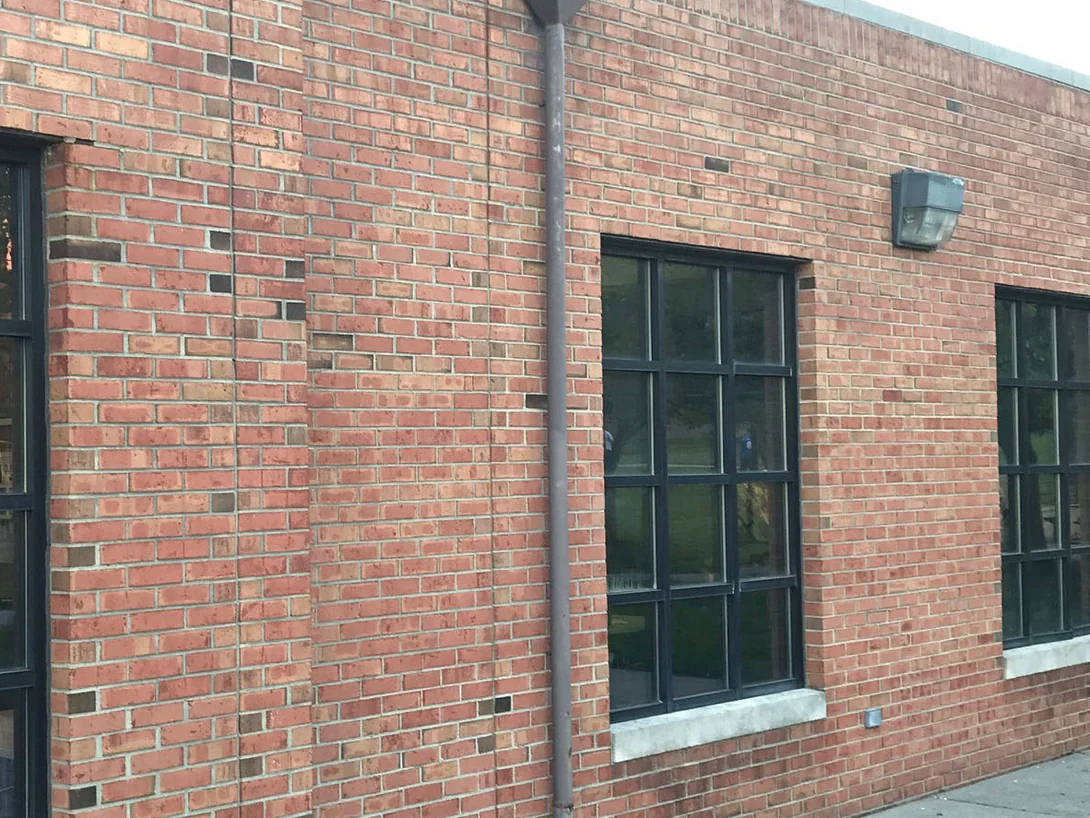 The same side elevation in 2019, the brick even from the pilaster past the downspout to the far windows, the frame carrying the Brickman Certified stamp