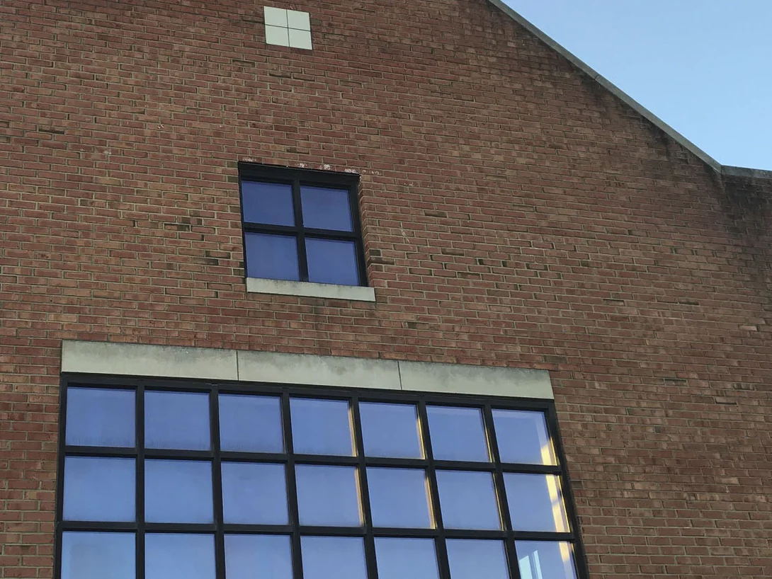 The same gable end wall in 2019 from the same viewpoint, the brick holding one red range across every course and around the small square window