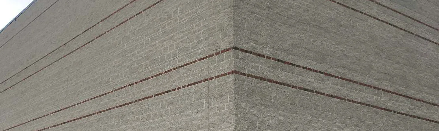 A band of the school's split face block wall in 2021, one pale range running past thin red brick banding courses
